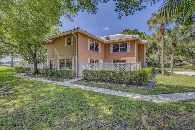 view of property exterior with a yard, a tile roof, fence, and stucco siding