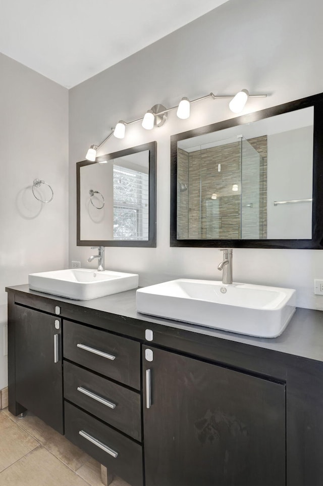 bathroom featuring a stall shower, double vanity, a sink, and tile patterned floors