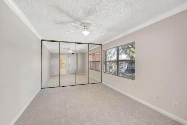 unfurnished bedroom with carpet flooring, baseboards, ornamental molding, and a textured ceiling