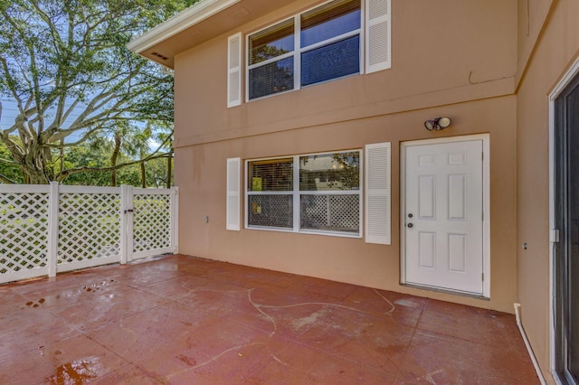 exterior space featuring a patio, stucco siding, fence, and a gate