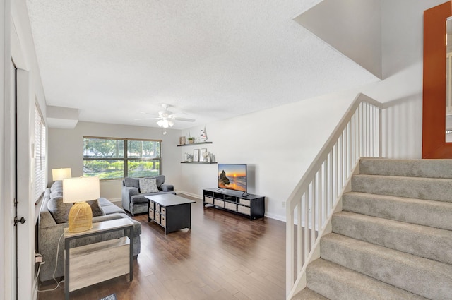 living area with baseboards, dark wood finished floors, stairway, a textured ceiling, and ceiling fan