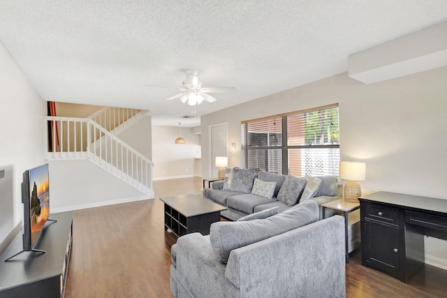 living room with dark wood-type flooring, ceiling fan, baseboards, and stairway