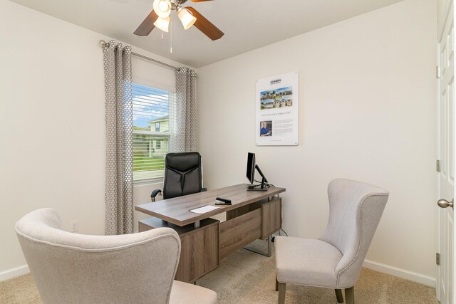 carpeted office space featuring baseboards and a ceiling fan