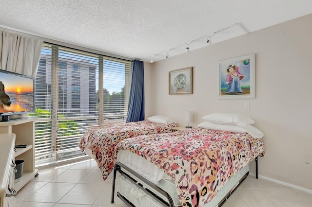 1625 Bridgewood Dr, Boca Raton, FL 33434 - bedroom with rail lighting, light tile patterned flooring, a textured ceiling, and baseboards