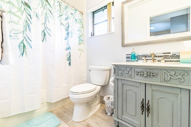 bathroom featuring baseboards, toilet, shower / bath combo with shower curtain, vanity, and wood finished floors