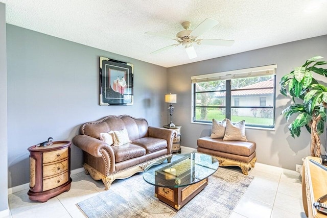 living room with a textured ceiling, light tile patterned floors, baseboards, and a ceiling fan