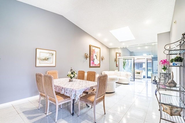 dining area featuring a skylight, high vaulted ceiling, light tile patterned flooring, and baseboards