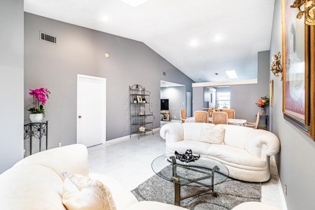 living area with light tile patterned floors, visible vents, baseboards, and vaulted ceiling