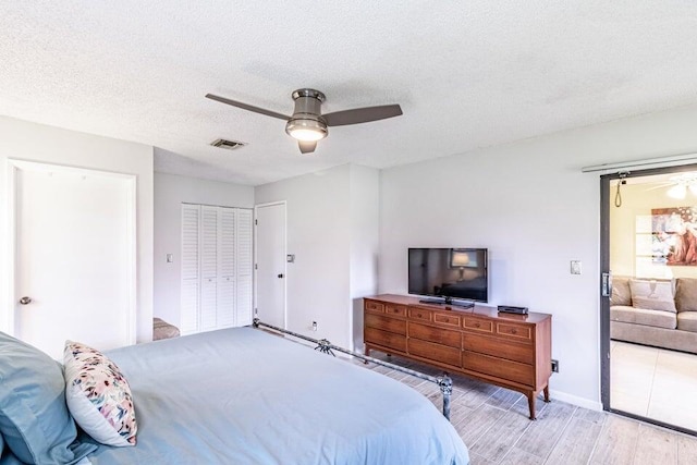 bedroom with visible vents, a ceiling fan, wood finished floors, and a textured ceiling