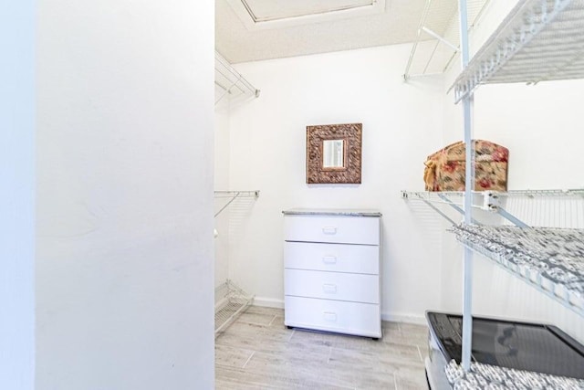 walk in closet with light wood-style floors