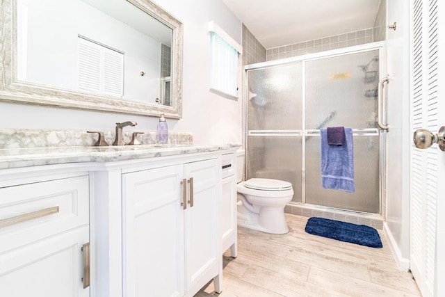 full bathroom with a shower stall, a closet, vanity, toilet, and wood finished floors