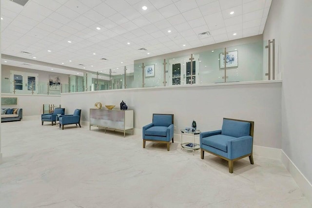 living area with baseboards, a drop ceiling, recessed lighting, visible vents, and marble finish floor