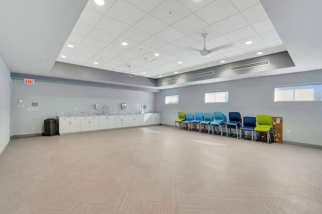 misc room featuring a raised ceiling, a healthy amount of sunlight, and baseboards