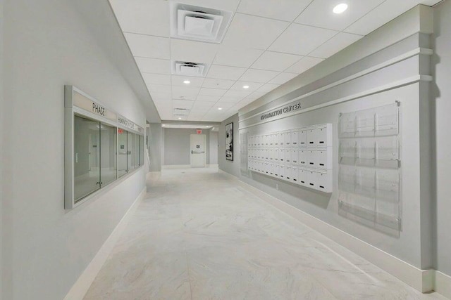 corridor featuring baseboards, mail area, a paneled ceiling, and recessed lighting