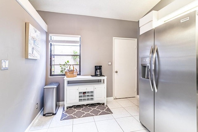 kitchen with stainless steel fridge with ice dispenser, baseboards, white cabinetry, and light tile patterned floors