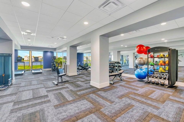 exercise room featuring carpet flooring, baseboards, a drop ceiling, and visible vents