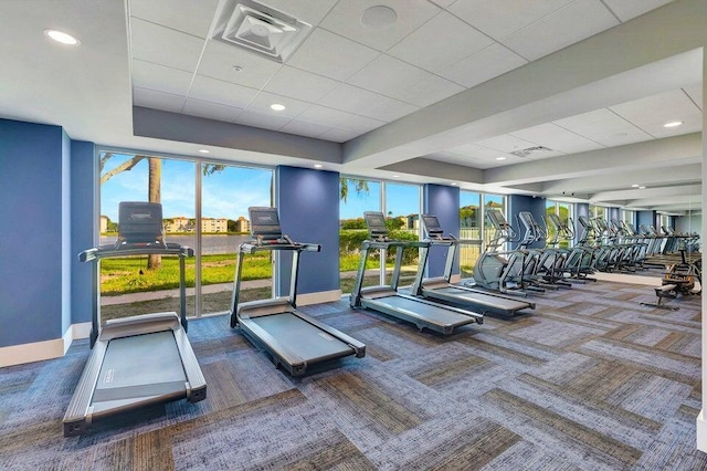 gym featuring a paneled ceiling, baseboards, carpet floors, visible vents, and a tray ceiling