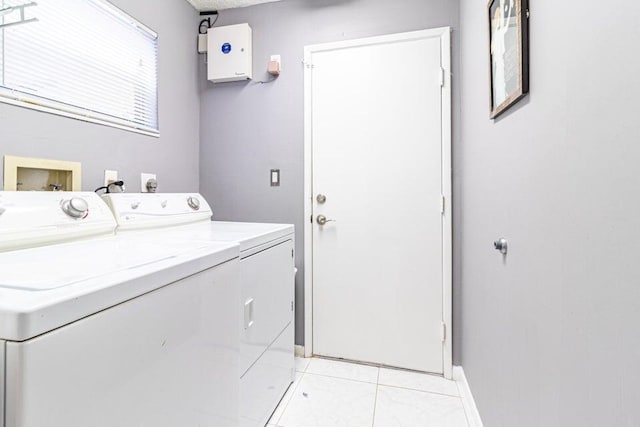 washroom featuring independent washer and dryer, light tile patterned flooring, laundry area, and baseboards