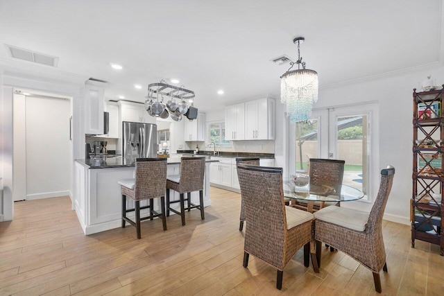 dining room featuring visible vents, light wood-type flooring, and an inviting chandelier