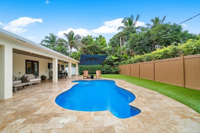 view of pool with an outdoor living space, ceiling fan, a fenced backyard, a patio, and a fenced in pool
