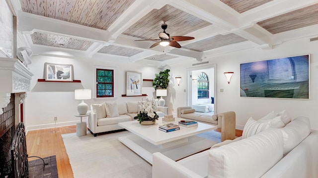 living area featuring a fireplace, a ceiling fan, beam ceiling, coffered ceiling, and hardwood / wood-style flooring