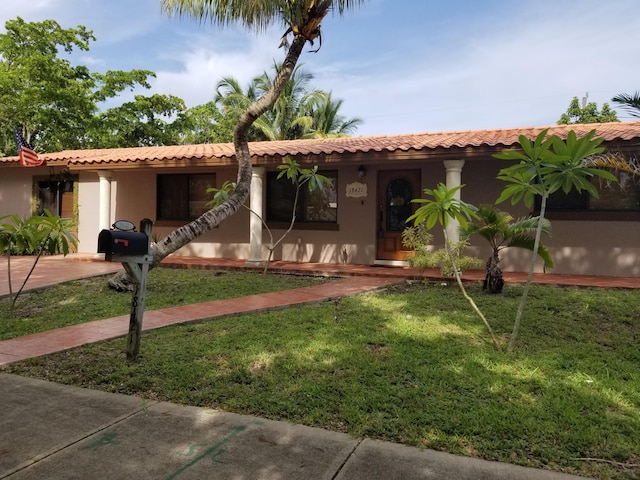 view of front of home featuring stucco siding, a tile roof, and a front yard