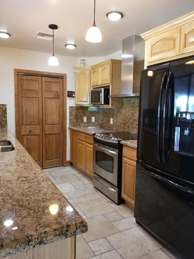 kitchen featuring stainless steel appliances, visible vents, wall chimney exhaust hood, and stone tile flooring