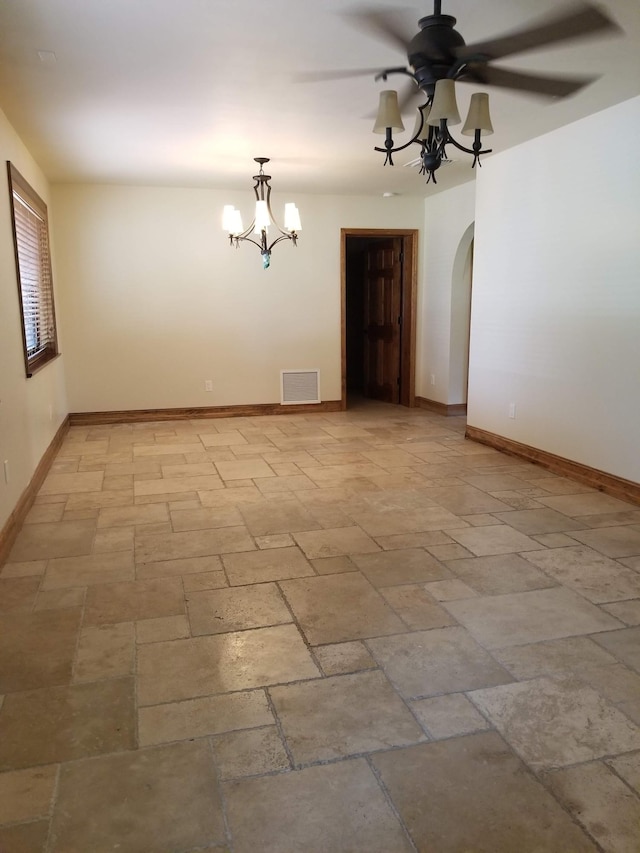 unfurnished room with arched walkways, ceiling fan with notable chandelier, baseboards, and visible vents