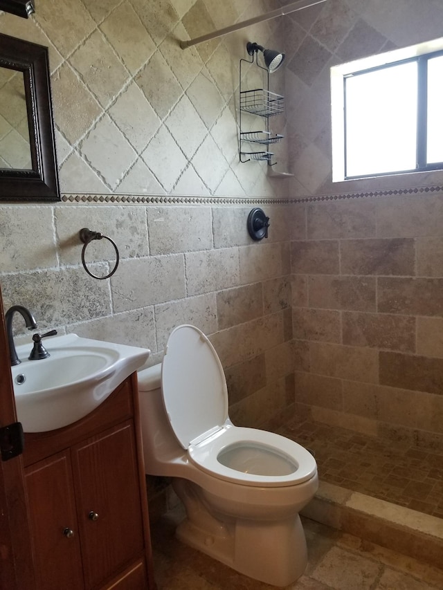 full bath featuring tiled shower, vanity, tile walls, and toilet