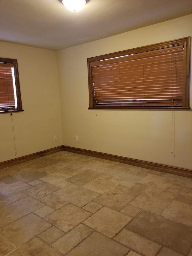empty room with baseboards and stone finish flooring