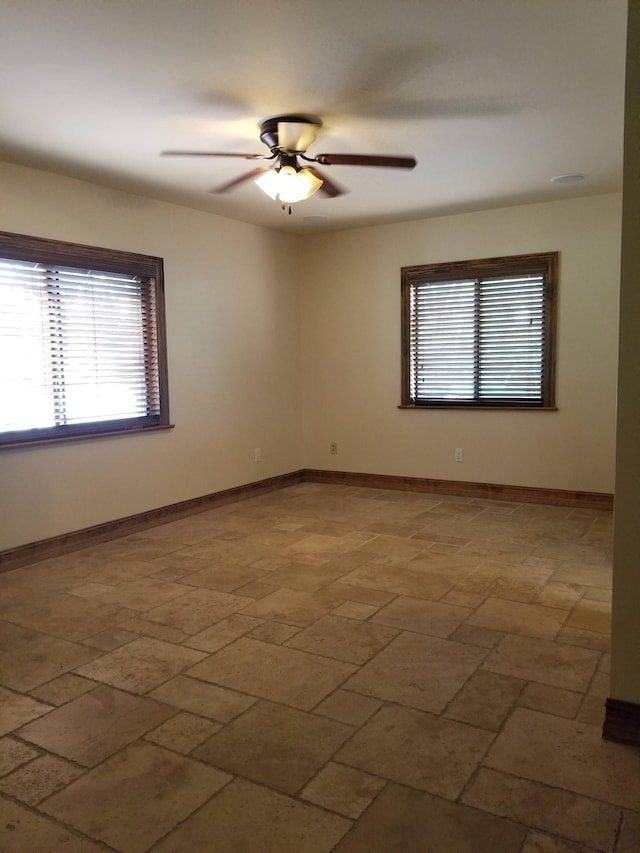 unfurnished room featuring ceiling fan, baseboards, and a healthy amount of sunlight