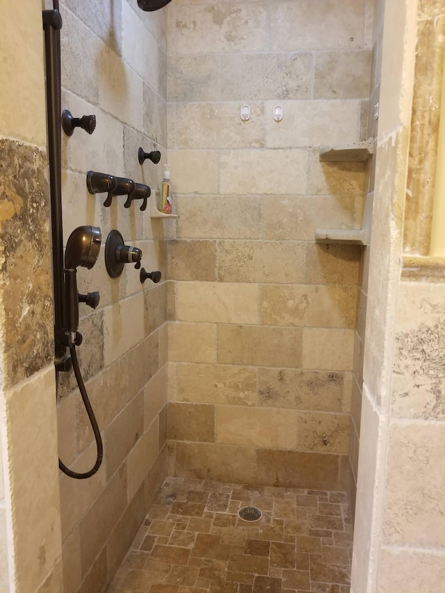 full bathroom with a tile shower and stone finish flooring