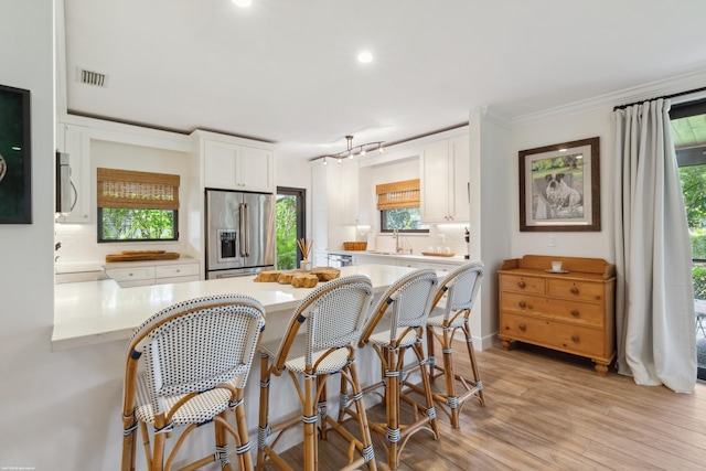 13268 Polo Club Rd Unit A104, Wellington, FL 33414 - kitchen with light wood-type flooring, a peninsula, white cabinetry, decorative backsplash, and stainless steel appliances