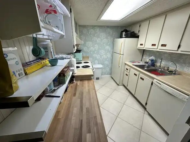 600 Executive Center Dr Unit 106, West Palm Beach, FL 33401 - kitchen featuring white appliances, white cabinetry, light countertops, a sink, and wallpapered walls