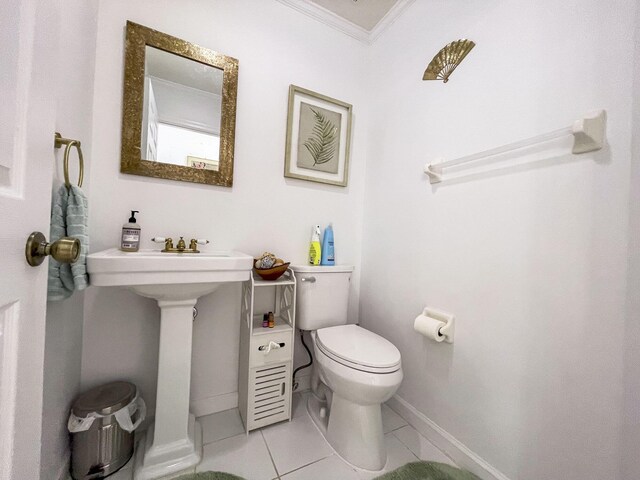 half bathroom with toilet, baseboards, ornamental molding, and tile patterned floors