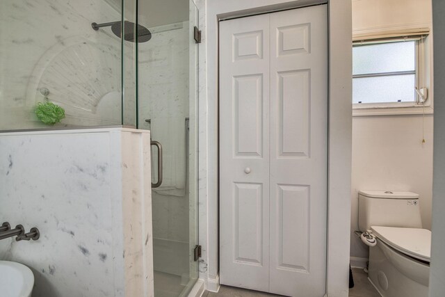 full bathroom featuring toilet, a marble finish shower, and a closet