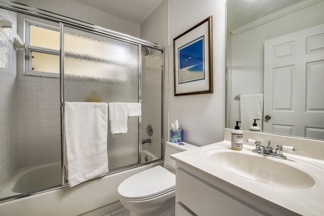 full bath featuring vanity, bath / shower combo with glass door, and toilet