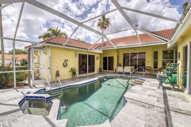 view of swimming pool featuring a patio, a pool with connected hot tub, and glass enclosure