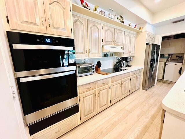 6582 Patio Ln, Boca Raton, FL 33433 - kitchen with stainless steel appliances, washing machine and dryer, under cabinet range hood, light countertops, and light wood-type flooring