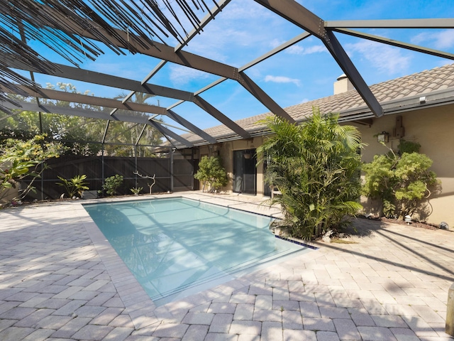 outdoor pool with a lanai, fence, and a patio area