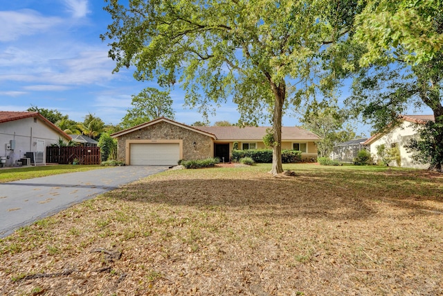 8933 NW 3rd Ct, Coral Springs, FL 33071 - ranch-style home with aphalt driveway, a front yard, fence, an attached garage, and central AC unit