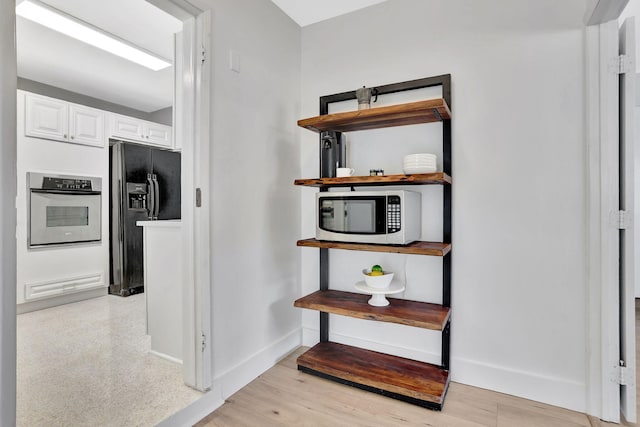 corridor with baseboards and light wood-style floors