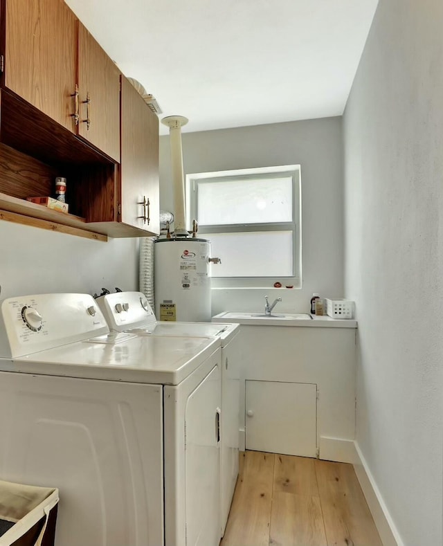 laundry area with water heater, independent washer and dryer, cabinet space, light wood-style flooring, and baseboards