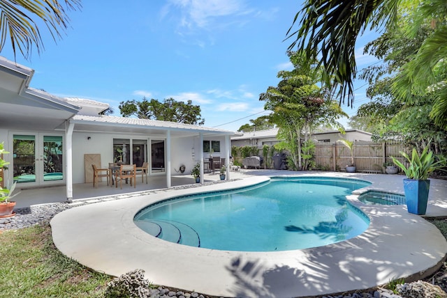 view of swimming pool with french doors, a patio area, fence, and a pool with connected hot tub