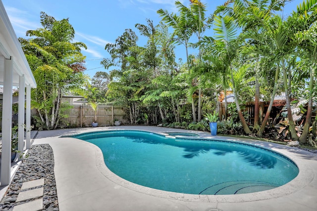 view of swimming pool featuring a fenced backyard and a pool with connected hot tub