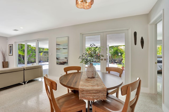 dining space with french doors, dark aggregate flooring, healthy amount of natural light, recessed lighting, and baseboards