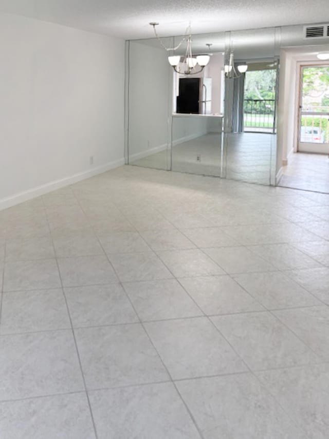 6935 Huntington Ln Unit 205, Delray Beach, FL 33446 - unfurnished room with a chandelier, baseboards, a textured ceiling, and light tile patterned floors