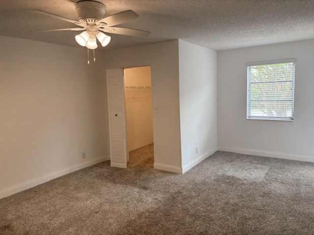 6935 Huntington Ln Unit 205, Delray Beach, FL 33446 - unfurnished bedroom with carpet flooring, a spacious closet, a textured ceiling, a closet, and a ceiling fan