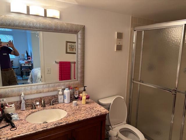 bathroom with toilet, a stall shower, ensuite bathroom, and vanity