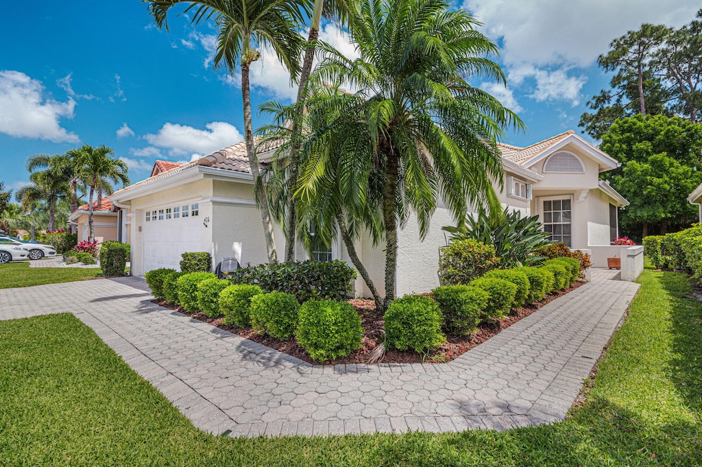 426 SW Horseshoe Bay, Port Saint Lucie, FL 34986 - view of property exterior with stucco siding, an attached garage, a yard, and a tile roof
